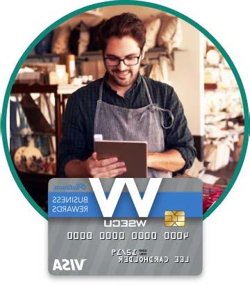 Store owner in apron holding tablet. Image of WSECU Platinum Business Rewards Visa card below. 